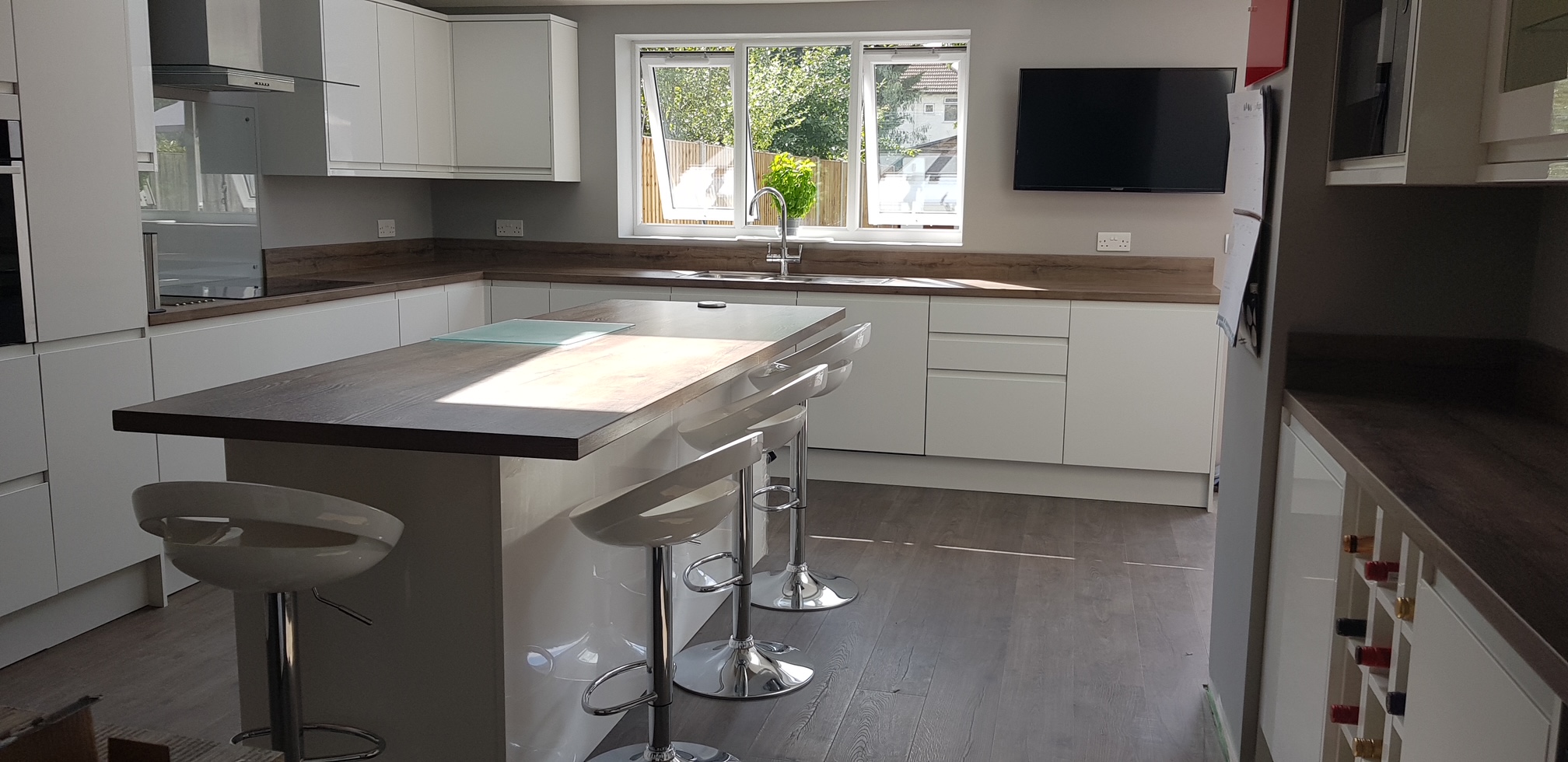 Completed kitchen extension — white gloss units, island with bar stools